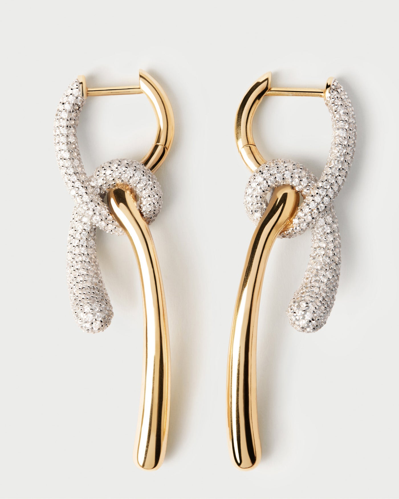 Pavé Twist hoops. Elegant asymmetric hoop earrings with contrasting pavé zirconia knotted pendants. Get the latest arrival from PDPAOLA. Place your order safely and get this Best Seller.